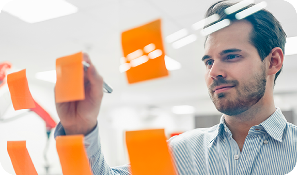 Man Writing On An Orange Sticky Note